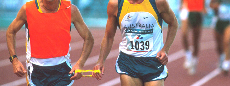A blind runner and his guide sharing a rope at the Paralympic Games.