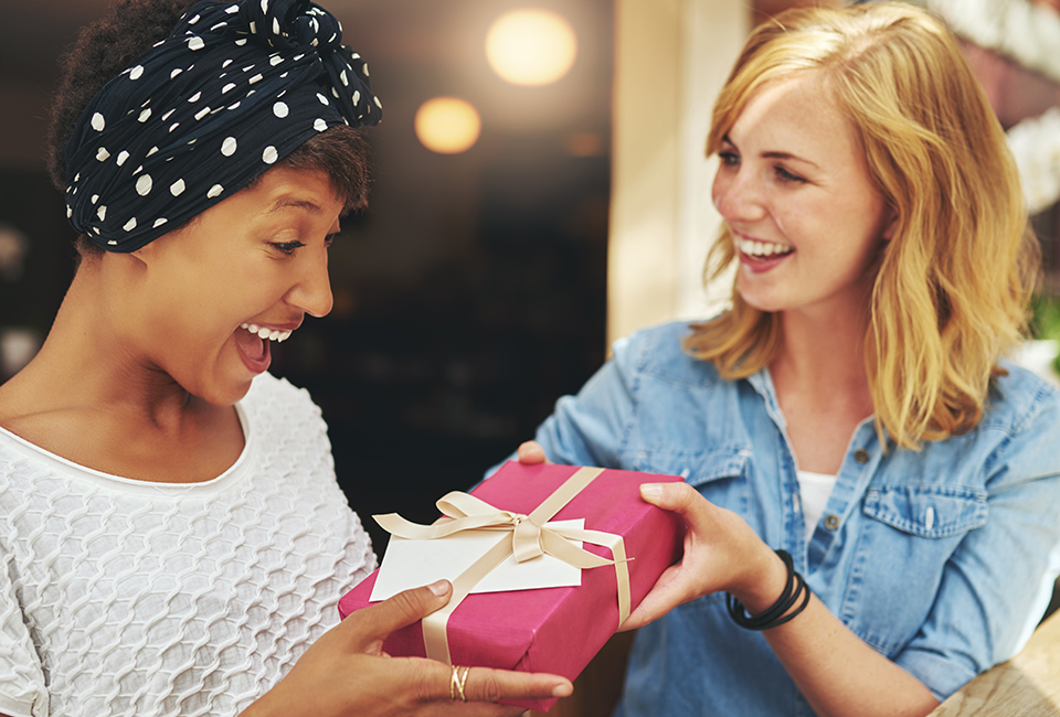 Two women excitedly exchange gifts.