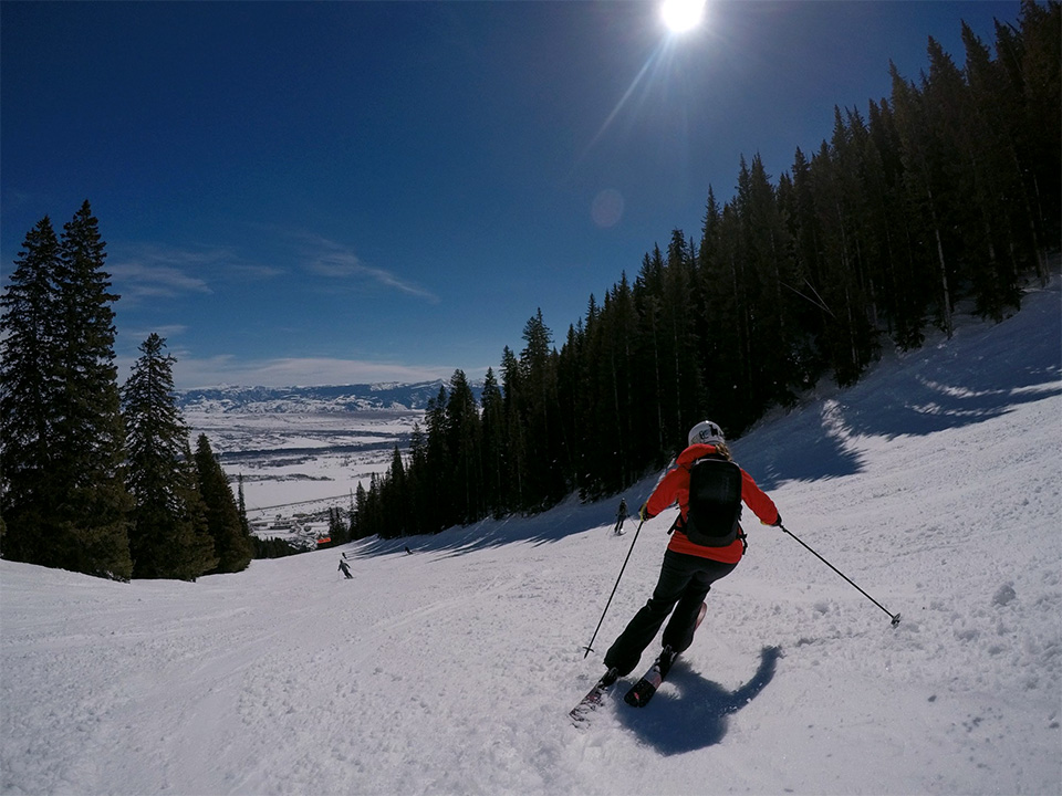 Photo of a woman on skis beginning her descent down a beautiful looking winter slope.