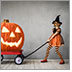 A little girl dressed up as a pumpkin witch pulls a red wagon with a huge jack-o-lantern inside it.