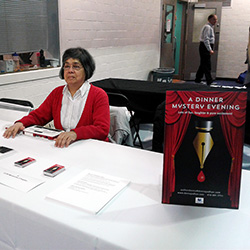 Donna Jodhan smiling while sitting at a table at one of her many Dinner Mystery Evening events.