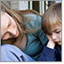 Photo of a mother sitting on the porch steps consoling her young son who appears to be sad.
