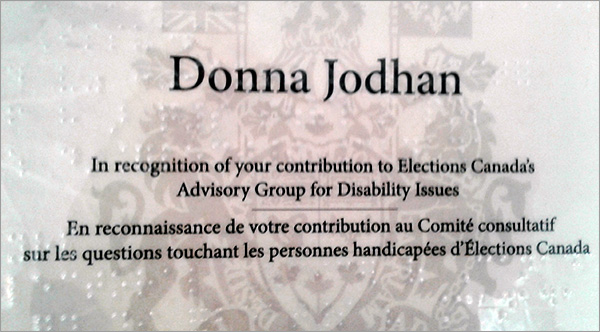 Photo of the award presented by Elections Canada to Donna Jodhan for contributions to Advisory Group for Disability. The award reads, In recognition of your contribution to Elections Canada's Advisory Group for Disability Issues. En reconnaissance de votre contribution au Comite' consultatif sur les questions touchant les personnes handicapees d'Elections Canada.