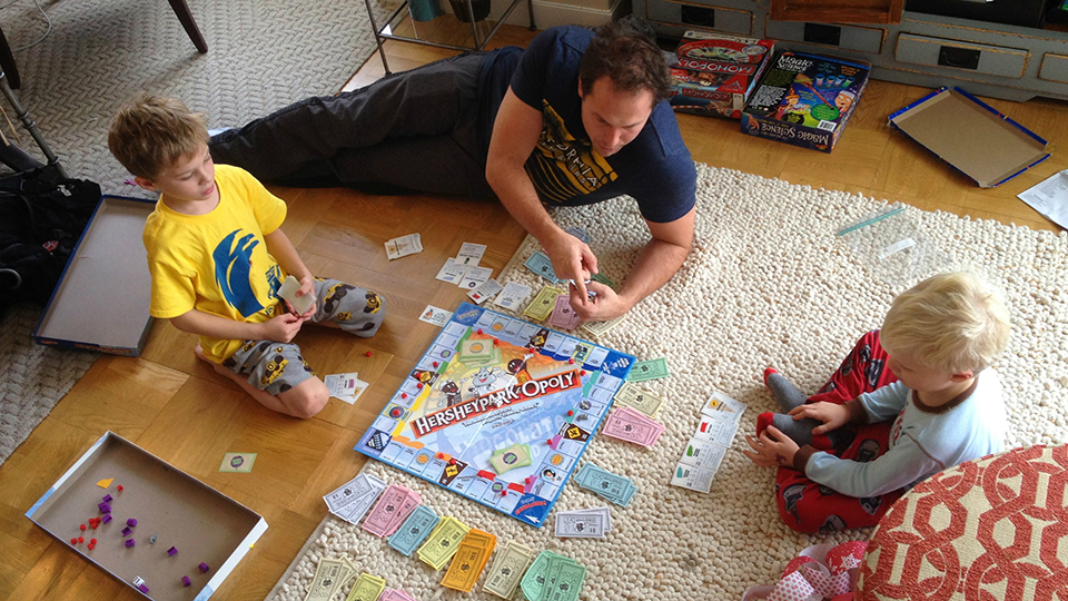 A father plays monopoly with his two children.