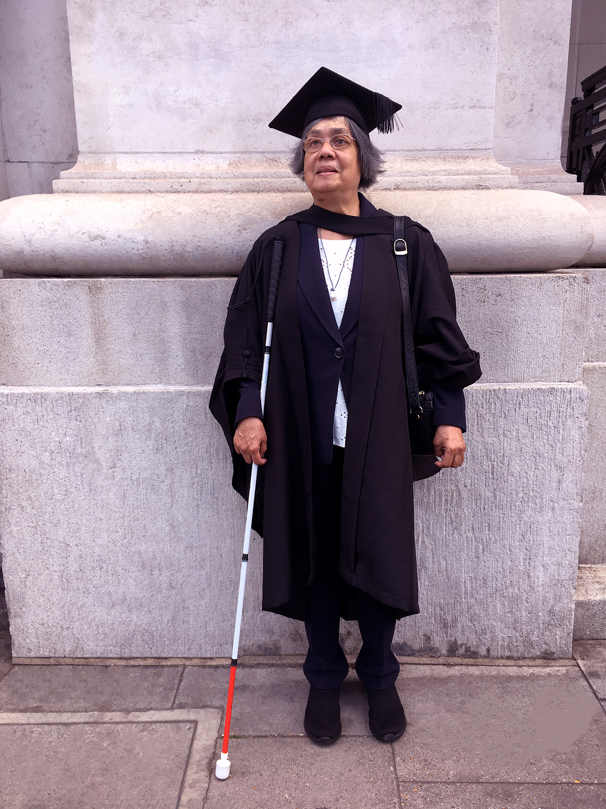 Donna Jodhan stands smiling in her cap and gown in front of the University of London England on July 14th 2022 where she was awarded her Law Degree.