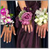 Three women stand together, arms outstretched, each showcasing a different corsage.