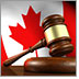 Gavel on a wooden desktop with a Canadian flag in the background.