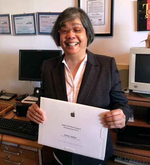 Donna Jodhan smiling while holding her Apple Certified Support Professional (ACSP) Certificate.