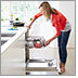 Photo of a woman standing in the middle of a large kitchen cleaning.